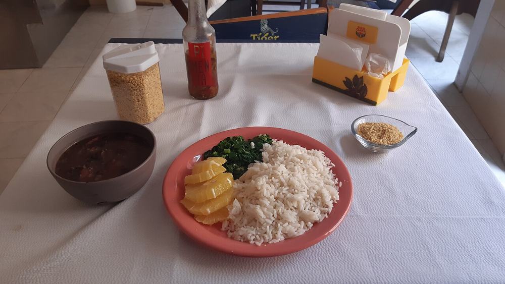 Prato feito com arroz, feijão, couve, laranja e farofa na mesa do restaurante